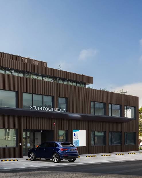 The two-storey dark timber-clad building of South Coast Medical in Dromana, with the practice name across the façade and on-site parking at the front entrance.
